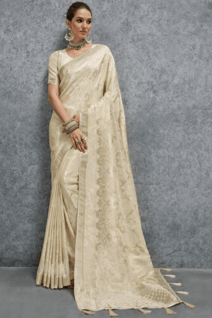 Elegant cream Banarasi silk saree with woven jacquard floral motifs and rich border, paired with matching blouse, perfect for wedding, festive and party wear.