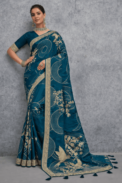 Teal blue Banarasi soft silk saree with gold zari woven floral and bird motifs, rich traditional border and designer pallu, perfect for wedding and festive wear.