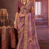 Woman wearing a lavender chinon silk saree with multicolor floral print and gold woven border styled with traditional necklace and earrings.
