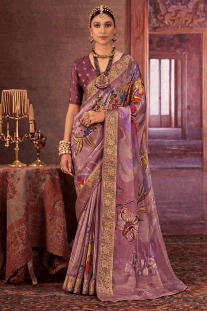 Woman wearing a lavender chinon silk saree with multicolor floral print and gold woven border styled with traditional necklace and earrings.
