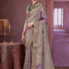 Elegant woman wearing a grey silk saree with golden zari border and purple floral prints, styled with traditional jewelry, standing in a royal vintage indoor setting.